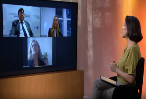 apresentadora de tv olhando para tela com três convidados entrevistados